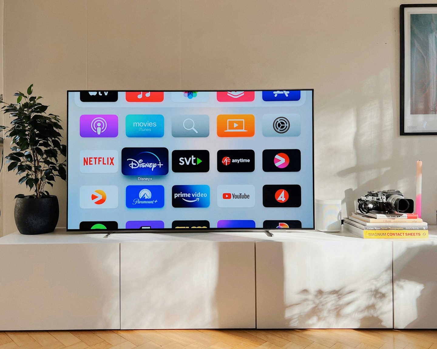 Flat-screen TV displaying streaming apps on white media console.