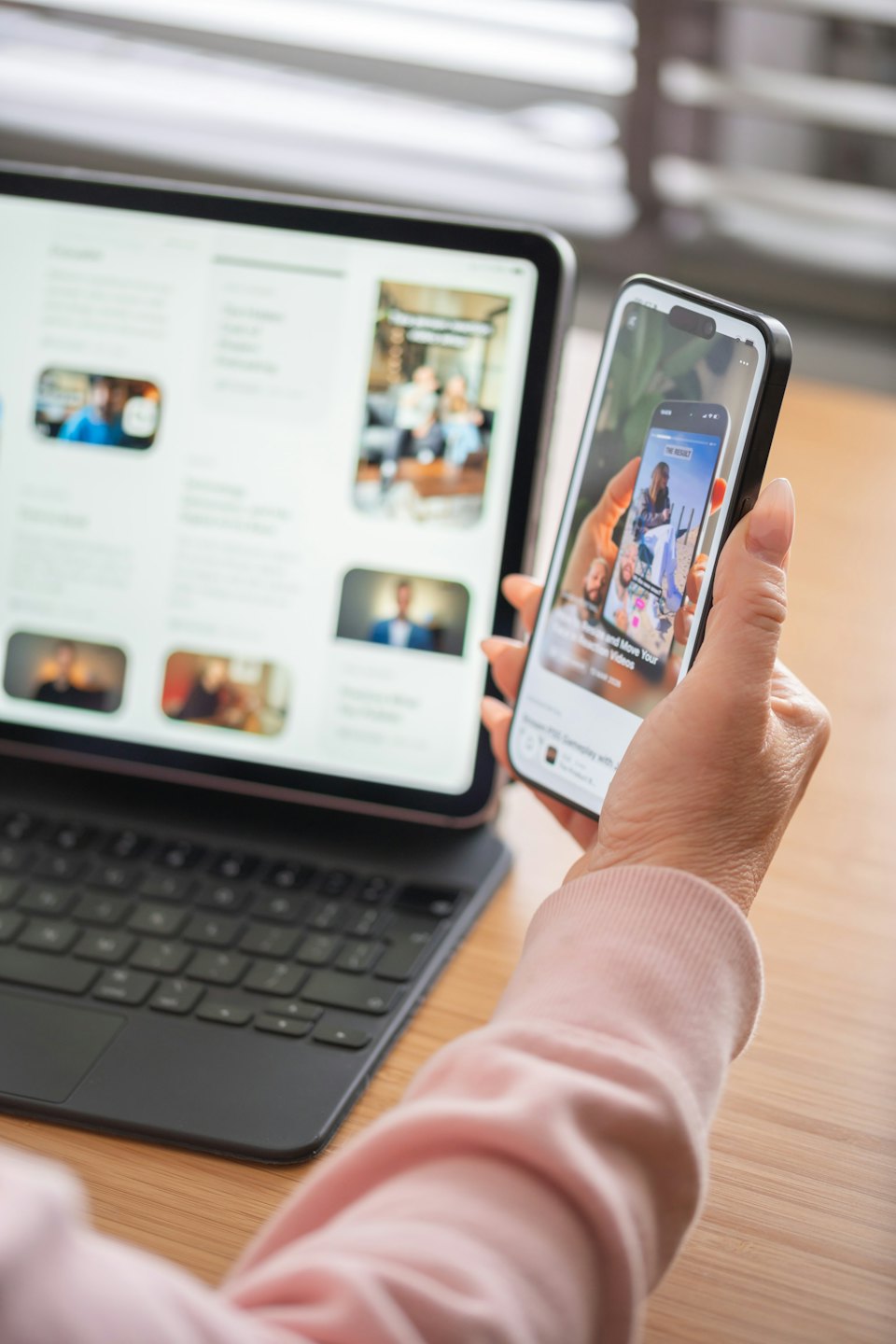 Person uses a smartphone while a tablet rests on the table.